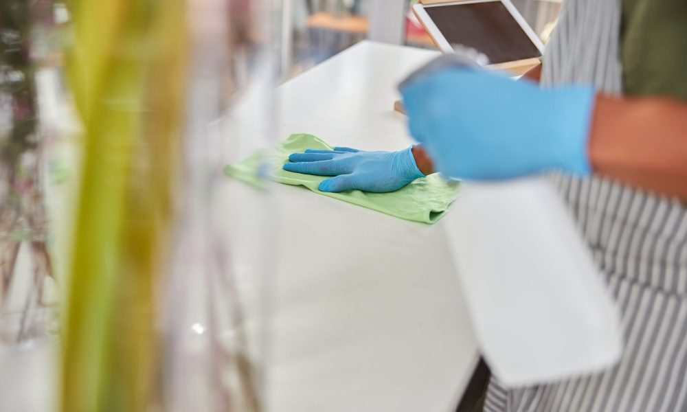 Top view cropped head close up of man in latex gloves doing desinfection in flower shop during quarantine